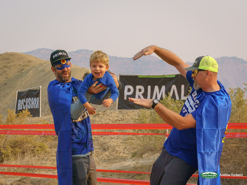 Fruita Race Yampa Two Adults With Capes Hold Up Toddler In Flying Position () Fruita Race Yampa Two Adults With Capes Hold Up Toddler In Flying Position ()